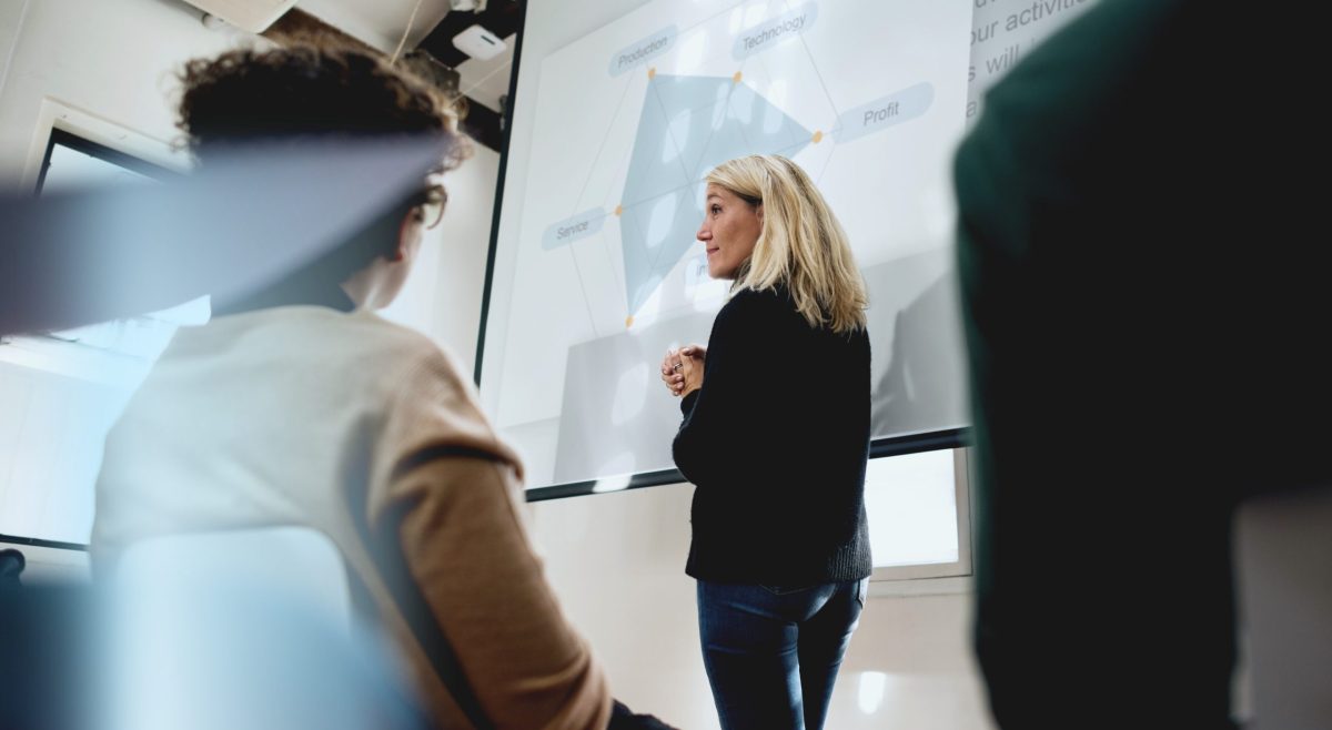 A,Woman,Presents,In,A,Meeting,Room,,Using,A,Projector.